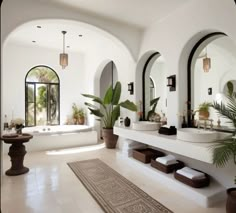 a large bathroom with two sinks and mirrors on the wall, along with potted plants