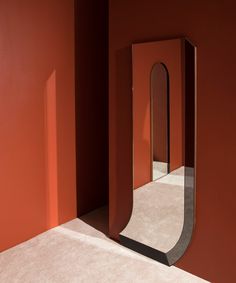 an empty room with red walls and a large mirror on the wall in front of it