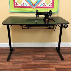 a sewing machine sitting on top of a table next to a wall hanging with a quilt