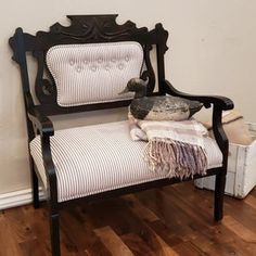 a bird sitting on top of a wooden bench next to a white and black striped chair