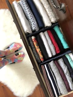 an open drawer with several pairs of shoes on top of it and various fabrics in the bottom