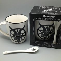 a ceramic cup and spoon in front of a boxed box with the same design on it