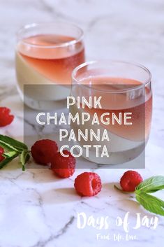 two glasses filled with pink champagne and raspberries