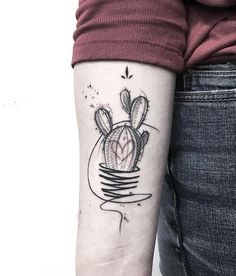 a small cactus tattoo on the left inner arm, with a heart in it's center