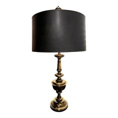 a black and gold lamp with a black shade on the top, against a white background