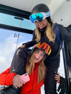 two women standing next to each other in front of a window with skis on