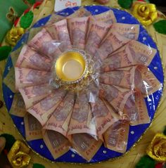 a blue plate topped with lots of money on top of a wooden table covered in gold foil