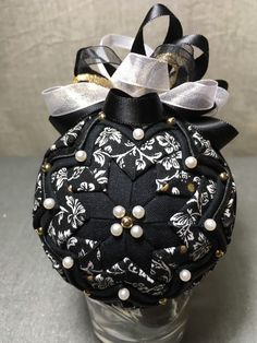 a black and white ornament with pearls on it sitting in a glass vase