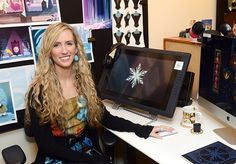 a woman sitting at a desk in front of a computer monitor with a snowflake on it