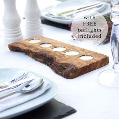 a wooden board sitting on top of a table next to plates and silverware with free tealight candles included