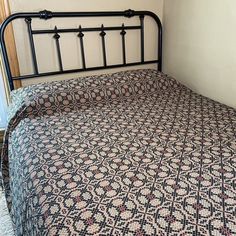 a bed with a black metal frame and patterned bedspread on top of it