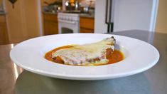 a white plate topped with meat covered in gravy on top of a kitchen counter