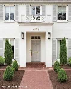 a large white house with some bushes in front of it