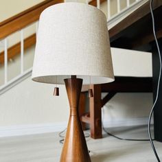 a wooden table lamp sitting on top of a hard wood floor next to a stair case