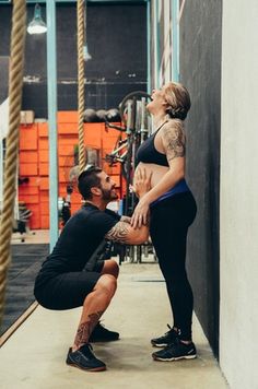 a man kneeling down next to a woman in a black top and leggings