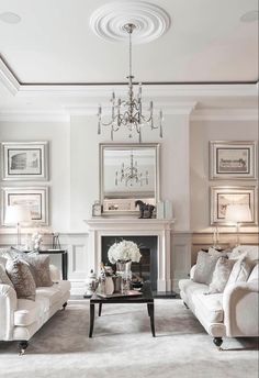 a living room filled with white furniture and a chandelier hanging from the ceiling