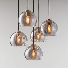 five clear glass globe pendant lights hanging from a ceiling