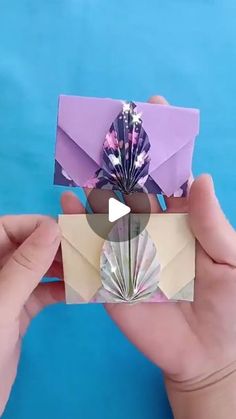 someone is holding an origami flower in front of a card that has been folded