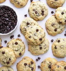 cookies and chocolate chips are arranged on a white surface with a bowl of chocolate chips