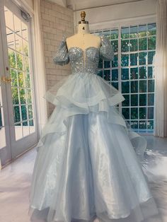 This enchanting handmade blue ball gown is perfect for a fairytale evening. The dress features a glittering sequin bodice with a deep V-neckline, complemented by voluminous puff sleeves for a touch of romantic elegance. The layered tulle skirt flows gracefully, adding a dramatic effect as you move. The back is adorned with a delicate lace-up closure, ensuring a perfect fit. Ideal for proms, galas, or any special occasion where you want to make a statement. Gown With Puff Sleeves, Skirt Corset, Blue Ball Gown, Big Skirts, Blue Ball Gowns, Floral Prom Dresses, Layered Tulle Skirt, Marine Uniform, Blue Ball