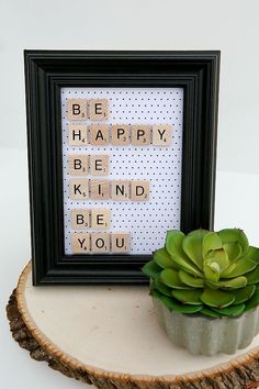 a small succulent sitting on top of a piece of wood next to a framed sign