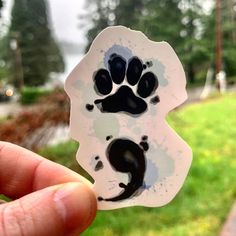 a person holding up a sticker with a cat paw on it's side