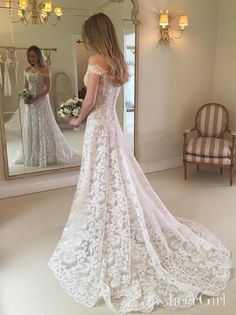 a woman standing in front of a mirror wearing a wedding dress