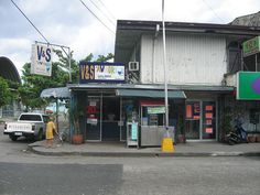 a person standing in front of a store on the side of a road next to a truck