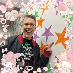 a man standing in front of a wall with stars on it and pointing to the side