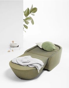 a modern daybed with pillows and blankets on it in front of a white wall