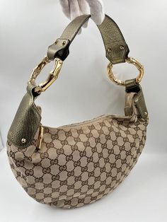 A Vintage Gucci Hobo made from brige canvas with the GG monogram. Gold metallic leather trim with gold embossed logo and gold hardware. Iconic bamboo detail on the shoulder strap and zip pull. The inside of the bag is in good condition and features an interior zipped pocket for valuables. The external fabric of this bag is also in very good condition. Inside there is the serial number on the back of the leather Gucci tab inside. Height: 21cm Width: 31cm Depth: 7cm Gucci Handbag Vintage, Cheap Brown Hobo Bag With Gold-tone Hardware, Luxury Vintage Bags With Gunmetal Hardware, Luxury Brown Shoulder Bag With Bamboo Handle, Luxury Hobo Bag With Gold-tone Hardware For Work, Luxury Brown Hobo Bag With Metal Hardware, Luxury Brown Bags With Branded Hardware, Luxury Brown Hand-tooled Shoulder Bag, Luxury Vintage Flap Shoulder Bag