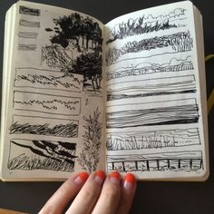 a hand is holding an open notebook with drawings on it and the pages are lined up