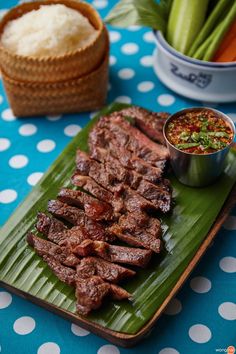 a green plate topped with meat next to a bowl of rice