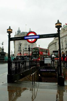 a red double decker bus driving down a street next to a sign that says underground