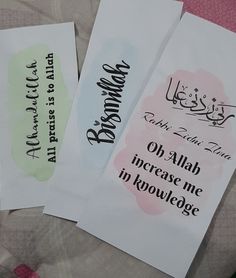 three cards with arabic writing on them sitting on a tablecloth covered surface, one has an envelope and the other has a handwritten message