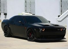 a black sports car parked in front of a white building with stairs leading up to it