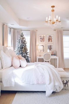 a bedroom with a white bed, chandelier and christmas tree in the corner