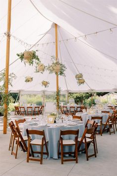 a large tent with tables and chairs set up for an outdoor wedding reception in the shade