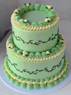 a three tiered cake with green frosting and flowers on it's sides