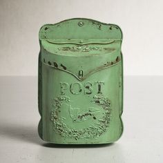 an old green post box sitting on top of a table