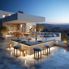 an outdoor dining area is lit up at night with candles on the tables and stools