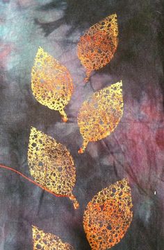 four yellow leaves are on a black fabric with red and gold paint splatters