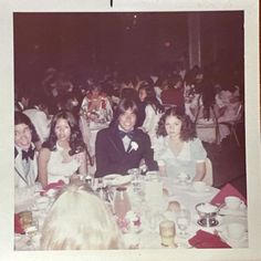 a group of people sitting around a table at a formal event in an old photo