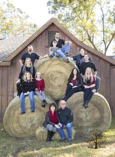 a group of people sitting on hay bales in front of a barn