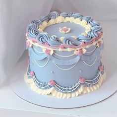 a blue cake with white frosting and pink decorations