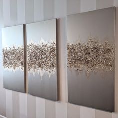 three silver paintings are hanging on the wall