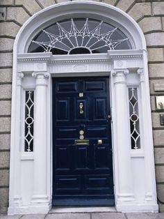 a green door with white trim and arched glass above the entrance to a brick building