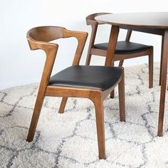 two wooden chairs sitting next to each other on top of a white carpeted floor