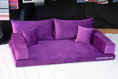 a purple couch sitting on top of a white bed