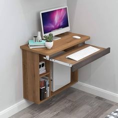 a computer desk with a monitor and keyboard on it in front of a white wall